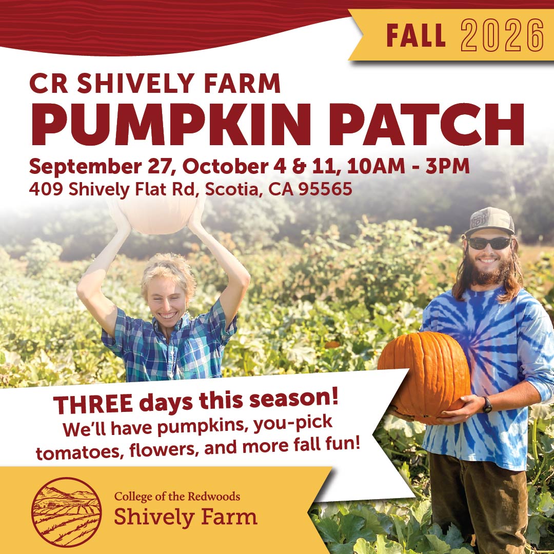 two students at the farm carrying pumpkins